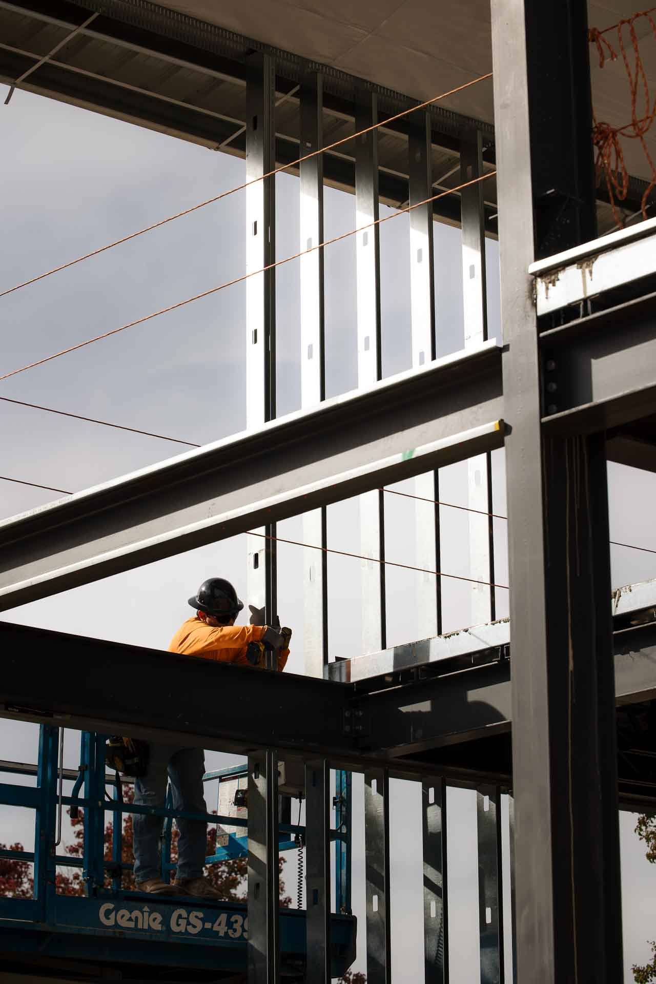 Structural steel frame going up on a Hall & Hill commercial build, with an ironworker on a lift